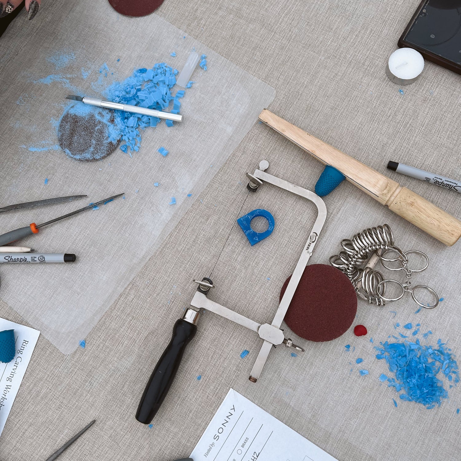 Workbench with jewelry-making tools and materials on a textured surface